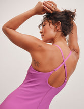 pink ribbed mini length dress with a soft scoop front neckline, back strap cross-over detail, overlapping front hem detail, and interior shorts with pockets.